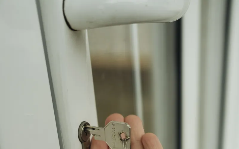 A hand holding house keys by a door lock